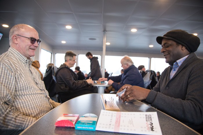 Mike Sudduth, left, plays a game of cribbage with Richard Franklin, right, as another game of cribbage takes place at the table next to them aboard the MV Sally Fox. Sudduth donated the specially inscribed boards as a way to honor his friend, Sally Fox, who was an advocate for passenger-only ferry service to Vashon Island and the vessel's namesake.