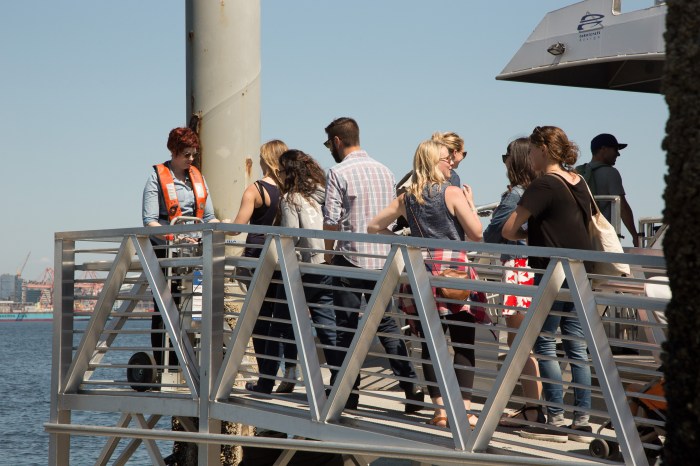 A deckhand scans tickets and passes of riders boarding the West Seattle ferry bound for Downtown Seattle.