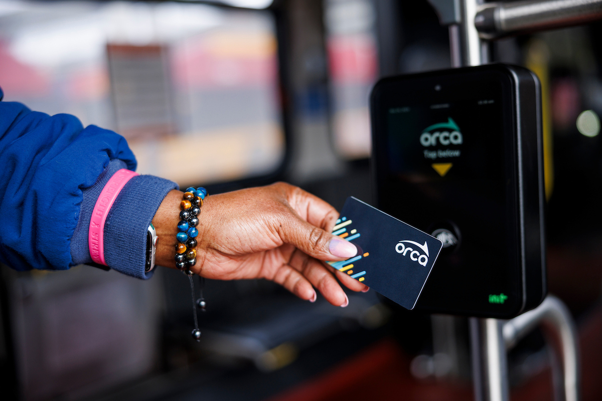 Transit customer hand tapping their ORCA card on a reader
