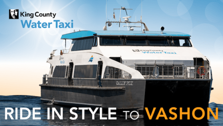 Water Taxi Sally Fox sailing into the Vashon Ferry Terminal. King County Water Taxi logo in the top left and Ride in Style to Vashon across the bottom